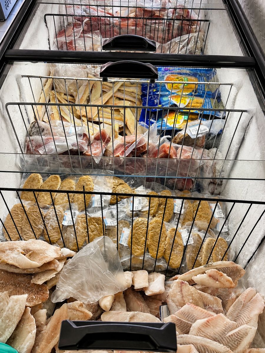 Cestos da vitrine com filés de tilápia e empanados de peixe